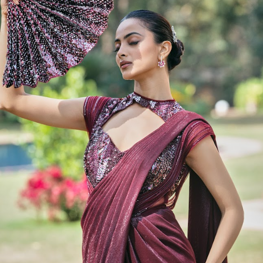 Woman in a maroon saree with a floral backdrop